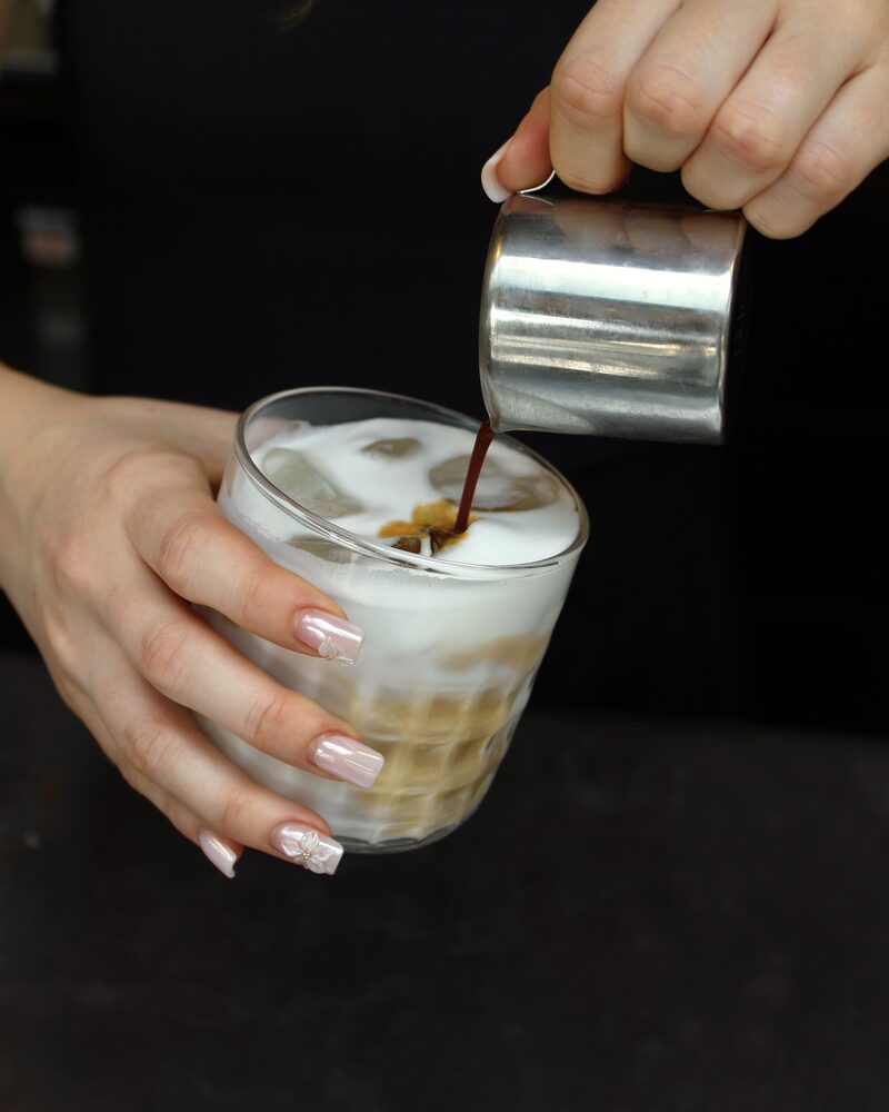 Barista eszpresszót önt jeges tejre egy üvegben